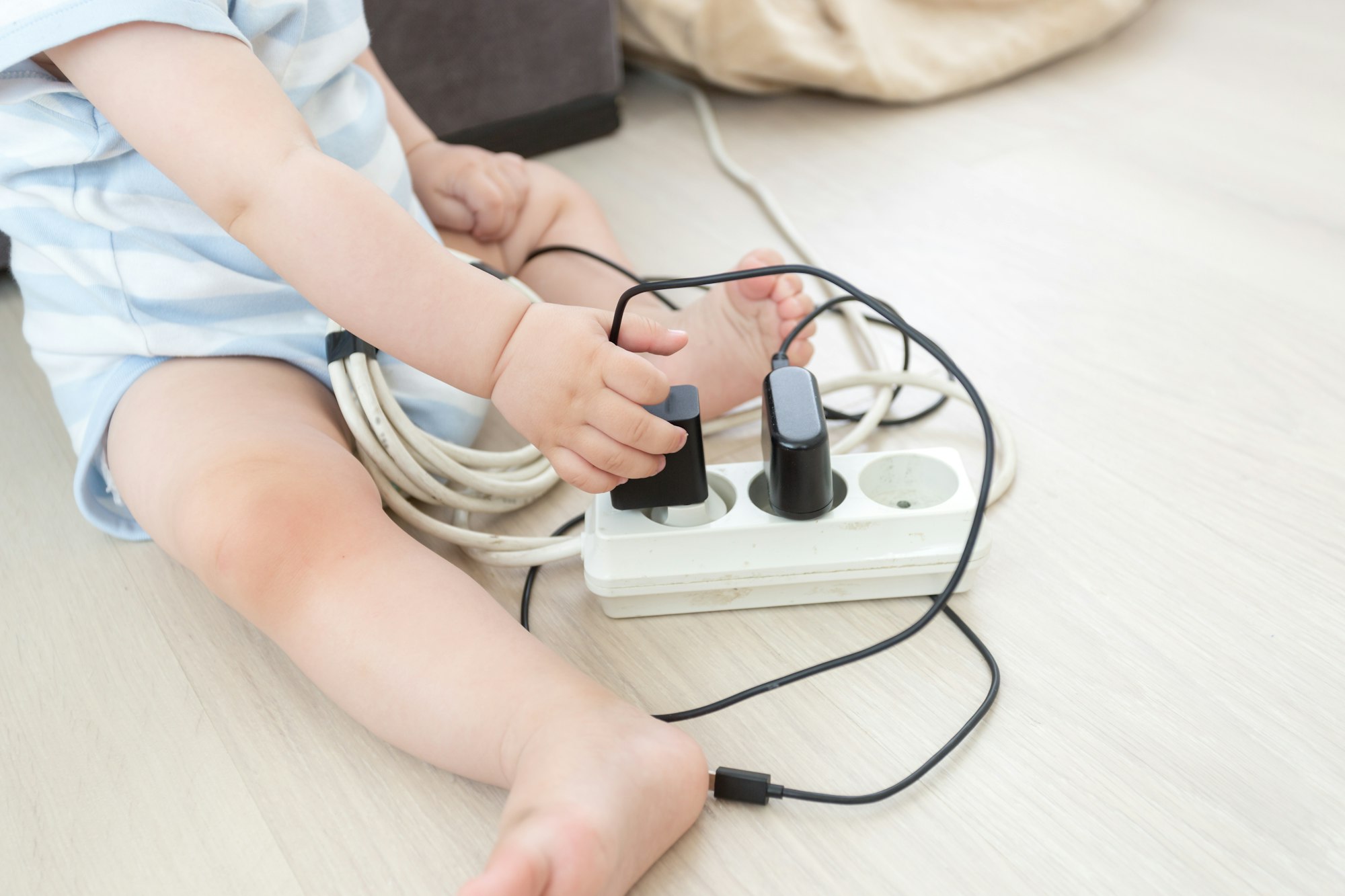 Closeup of baby boy pulling out cables from electrical extension